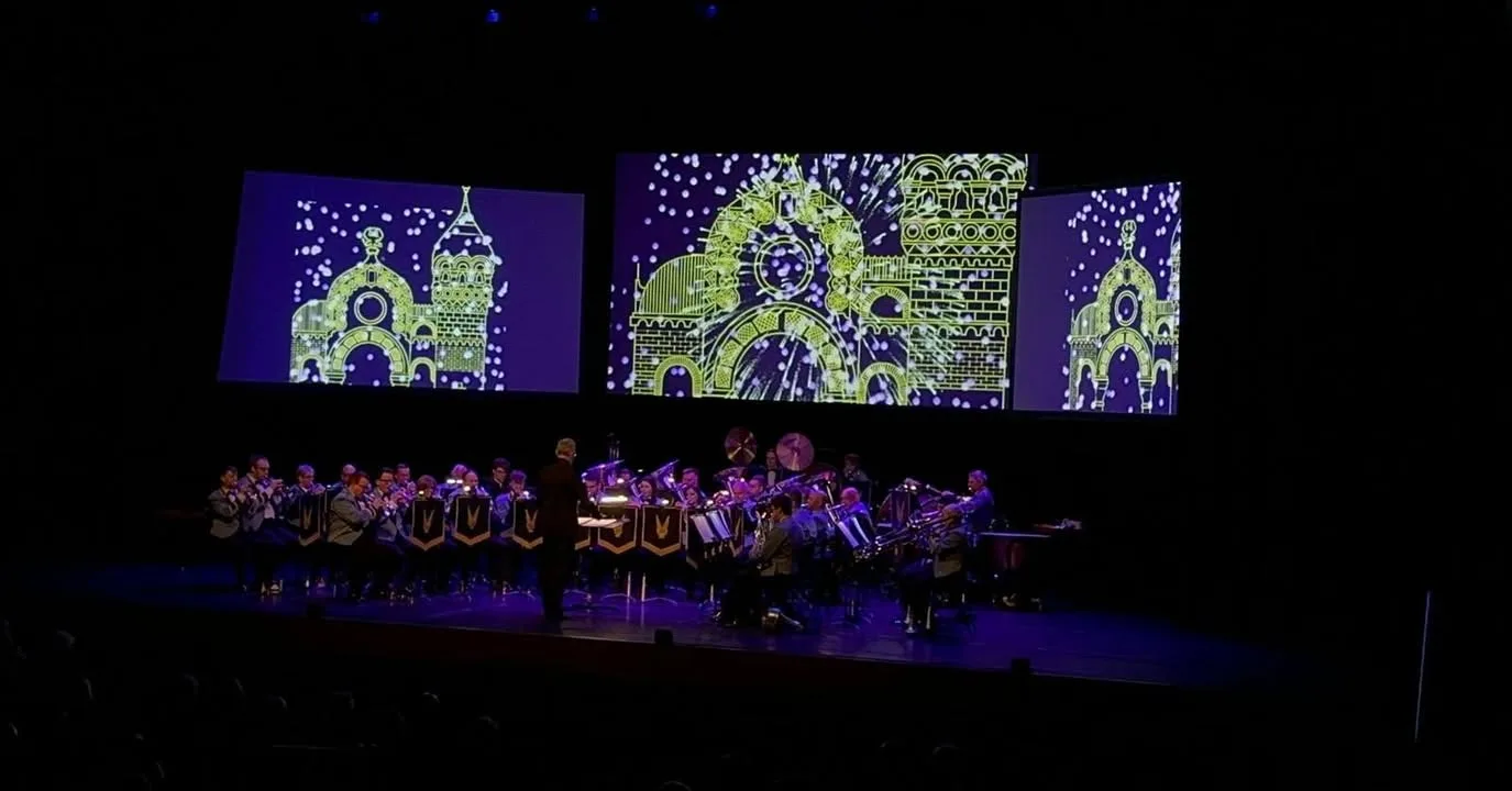 The KNDS Fairey Band performing with animated visuals projected across three screens