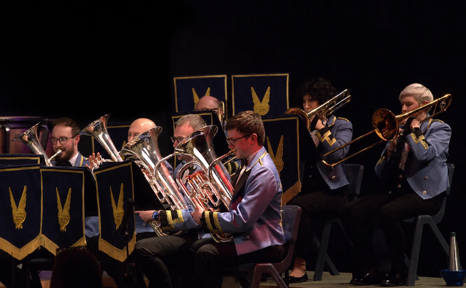 KNDS Fairey Band brass and percussion players performing on stage